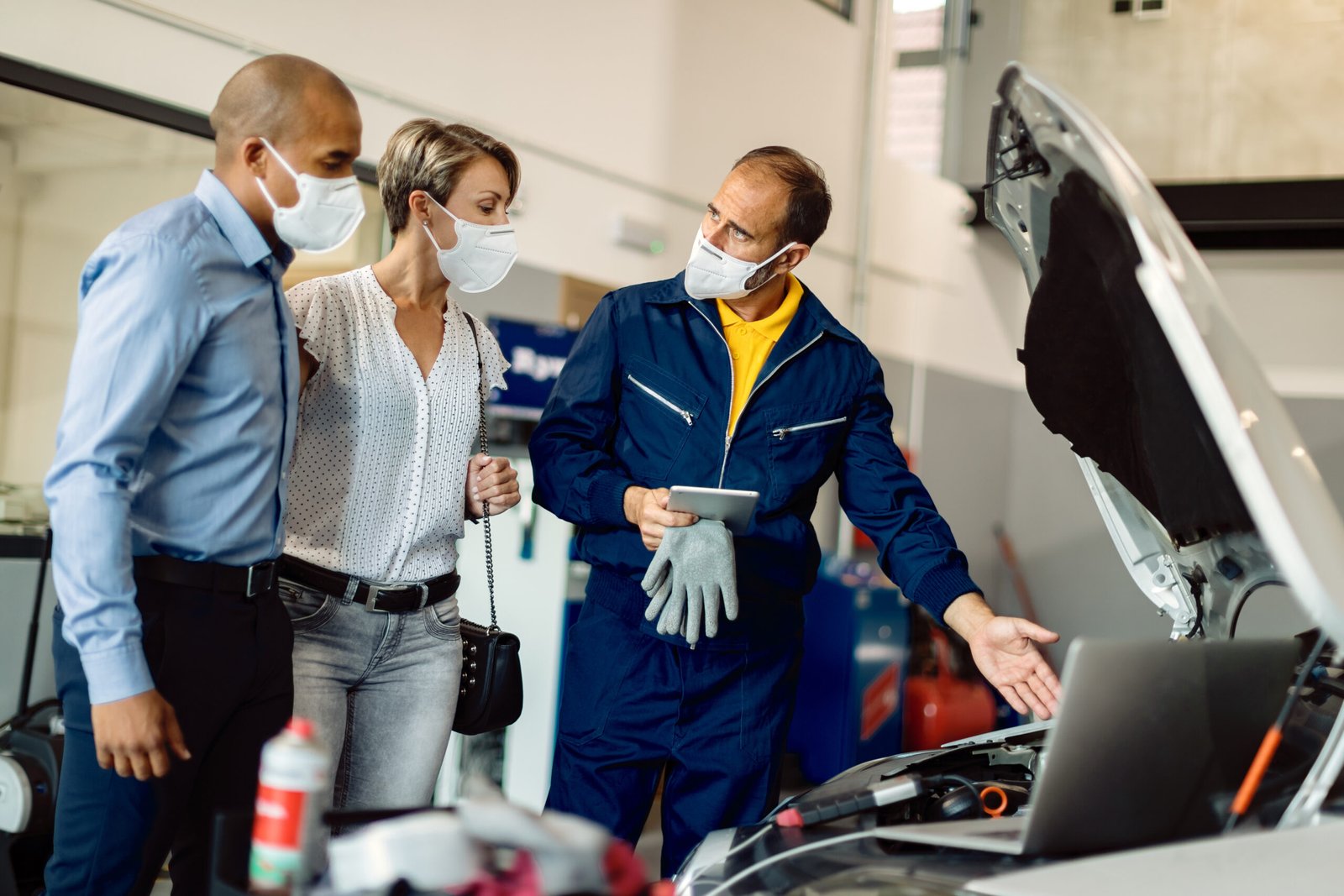 Auto mechanic and his customers talking while examining vehicle
